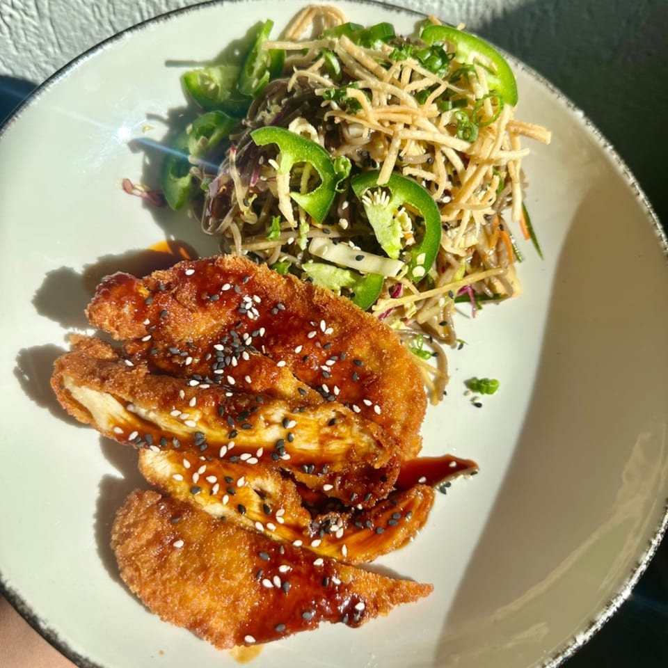 Crispy chicken with sweet sauce and sesame seeds, alongside a noodle salad with jalapeños.