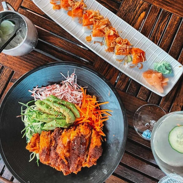 E+O Kitchen's crispy chicken, avocado, and shredded vegetables with sushi rolls and cocktails.