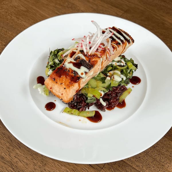 E+O Kitchen's salmon with black rice, bok choy, and radish, drizzled with sauces.