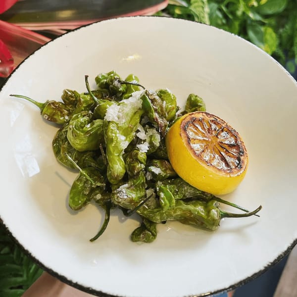 E+O Kitchen's blistered shishito peppers with flaky sea salt and a grilled lemon half.